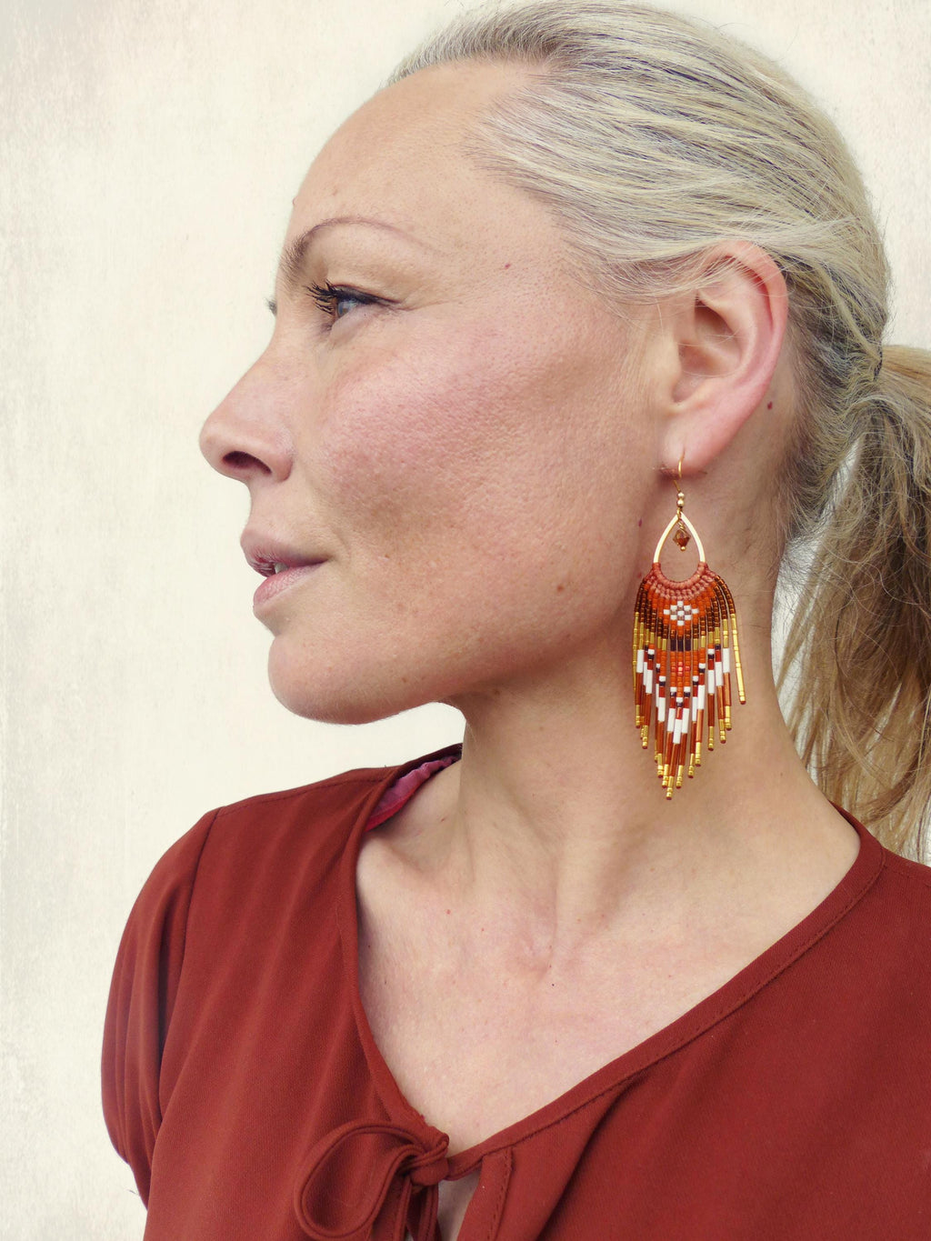 Peut inclure: Boucles d'oreilles en perles orange, blanches et dorées. Elles présentent un motif géométrique en forme de goutte d'eau et des accents métalliques dorés. Elles sont suspendues à un crochet doré. Un accessoire saisissant.