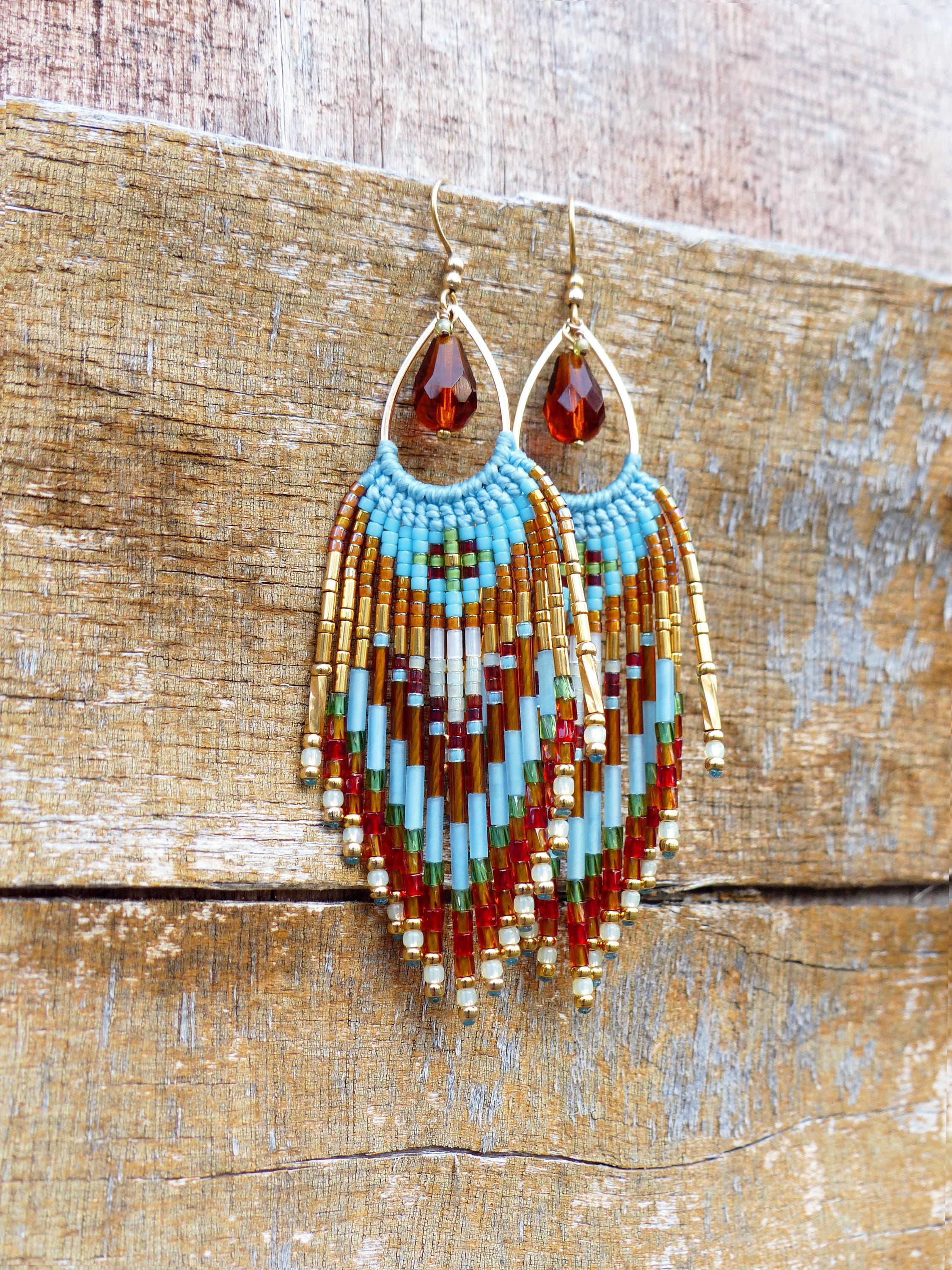 Peut inclure: Boucles d'oreilles faites à la main avec des perles en forme de goutte d'eau. Les boucles d'oreilles présentent une monture en fil doré avec une perle en forme de goutte marron. La frange perlée comprend des perles turquoise, marron, rouges et dorées.
