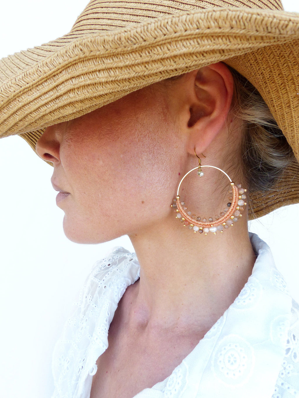 Peut inclure: Une paire de grandes boucles d'oreilles créoles avec un cadre en fil d'or et des perles de couleur pêche. Les perles sont entrecoupées de petites perles dorées et d'une seule perle blanche.