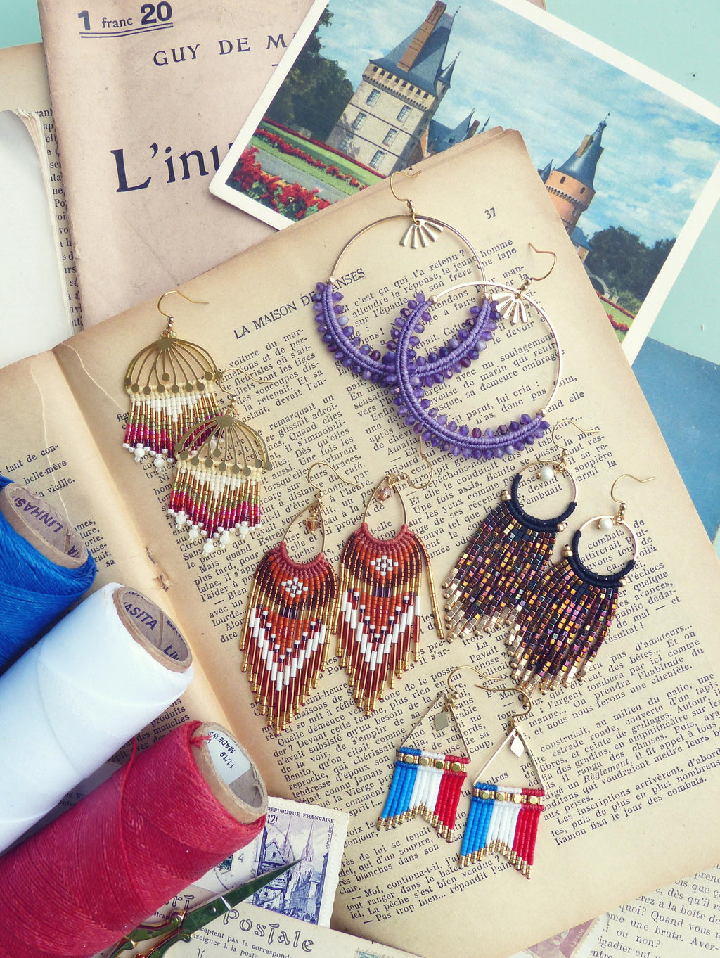 Peut inclure: Diverses boucles d'oreilles artisanales sur une page de livre ancien. Styles : franges perlées, créoles violettes et modèles aux couleurs du drapeau français.
