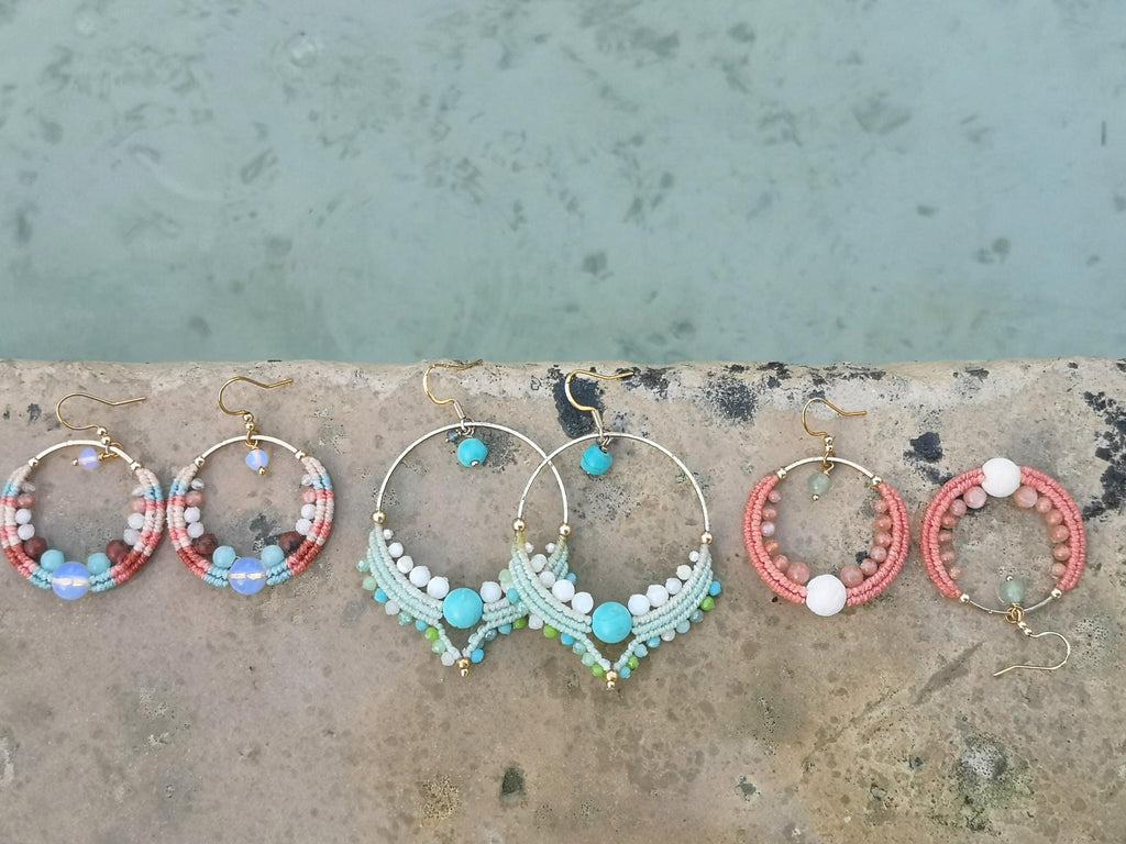 Peut inclure: Six paires de boucles d'oreilles créoles faites à la main avec des crochets dorés. Les boucles d'oreilles présentent divers motifs avec des perles colorées et des détails en macramé. Les couleurs incluent le corail, le turquoise, le blanc et le marron.