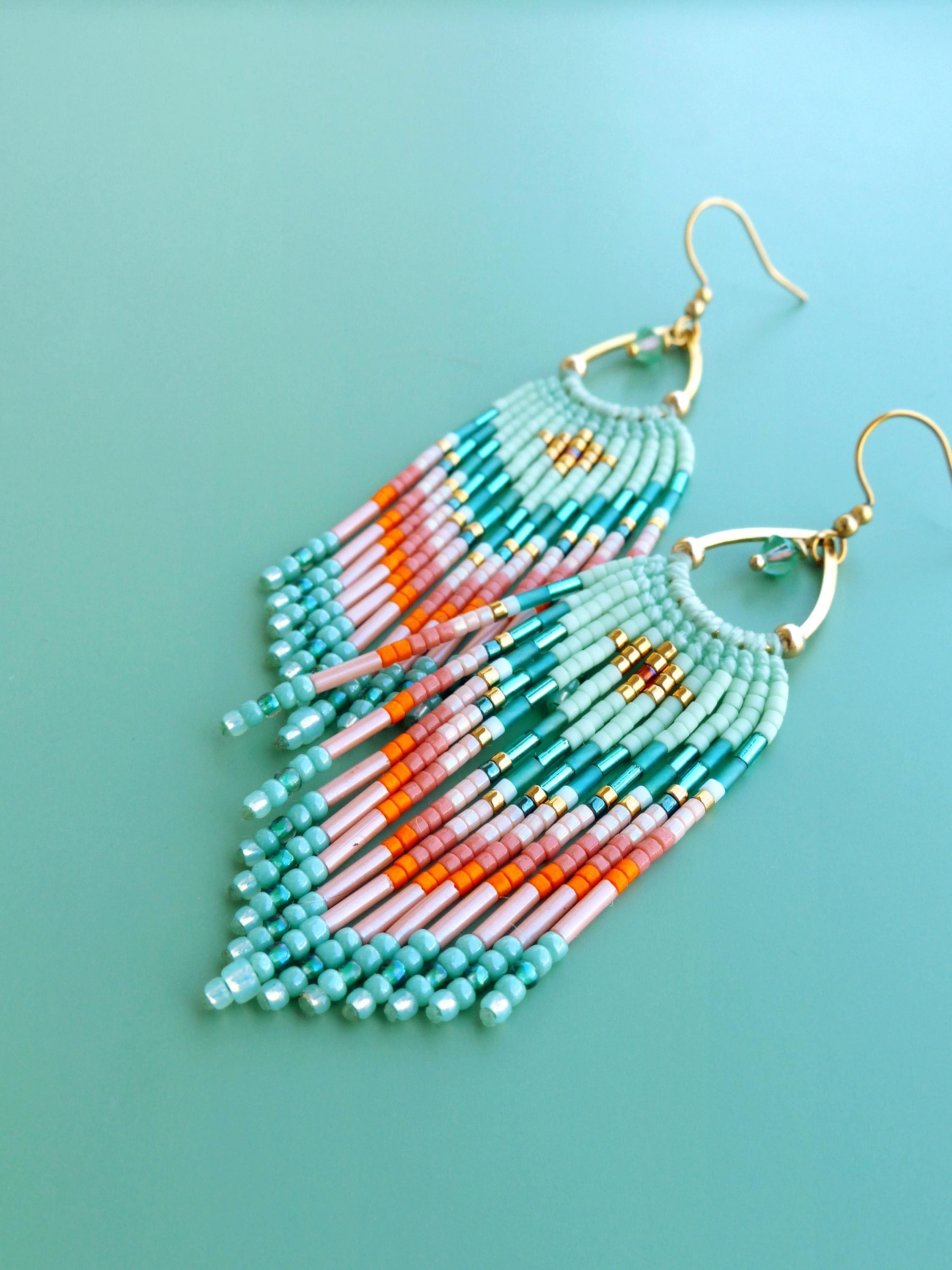 Peut inclure: Une paire de boucles d'oreilles pendantes composées de perles de rocaille en éventail dans des tons vert menthe, rose pâle et orange vif. Les perles sont tissées en franges suspendues à des arches et des crochets en métal doré.