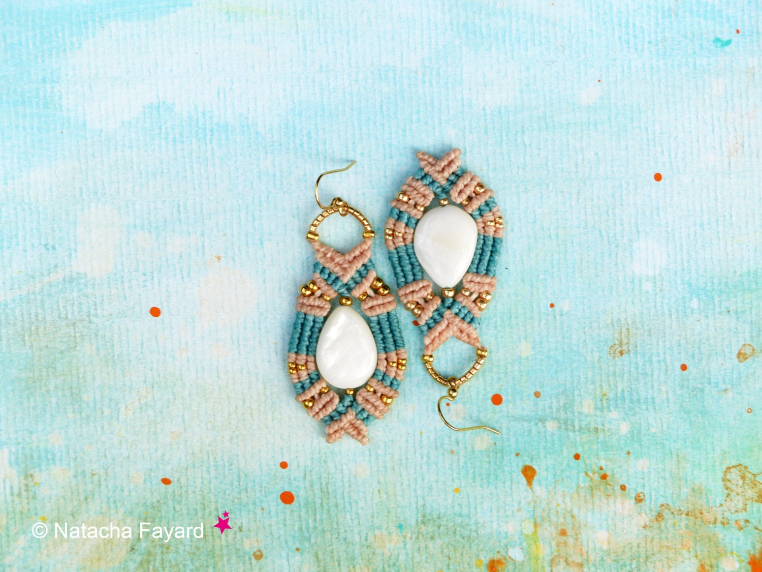 Peut inclure: Une paire de boucles d'oreilles en macramé turquoise et pêche avec des accents de coquillages blancs. Les boucles d'oreilles sont suspendues sur un fond bleu clair.