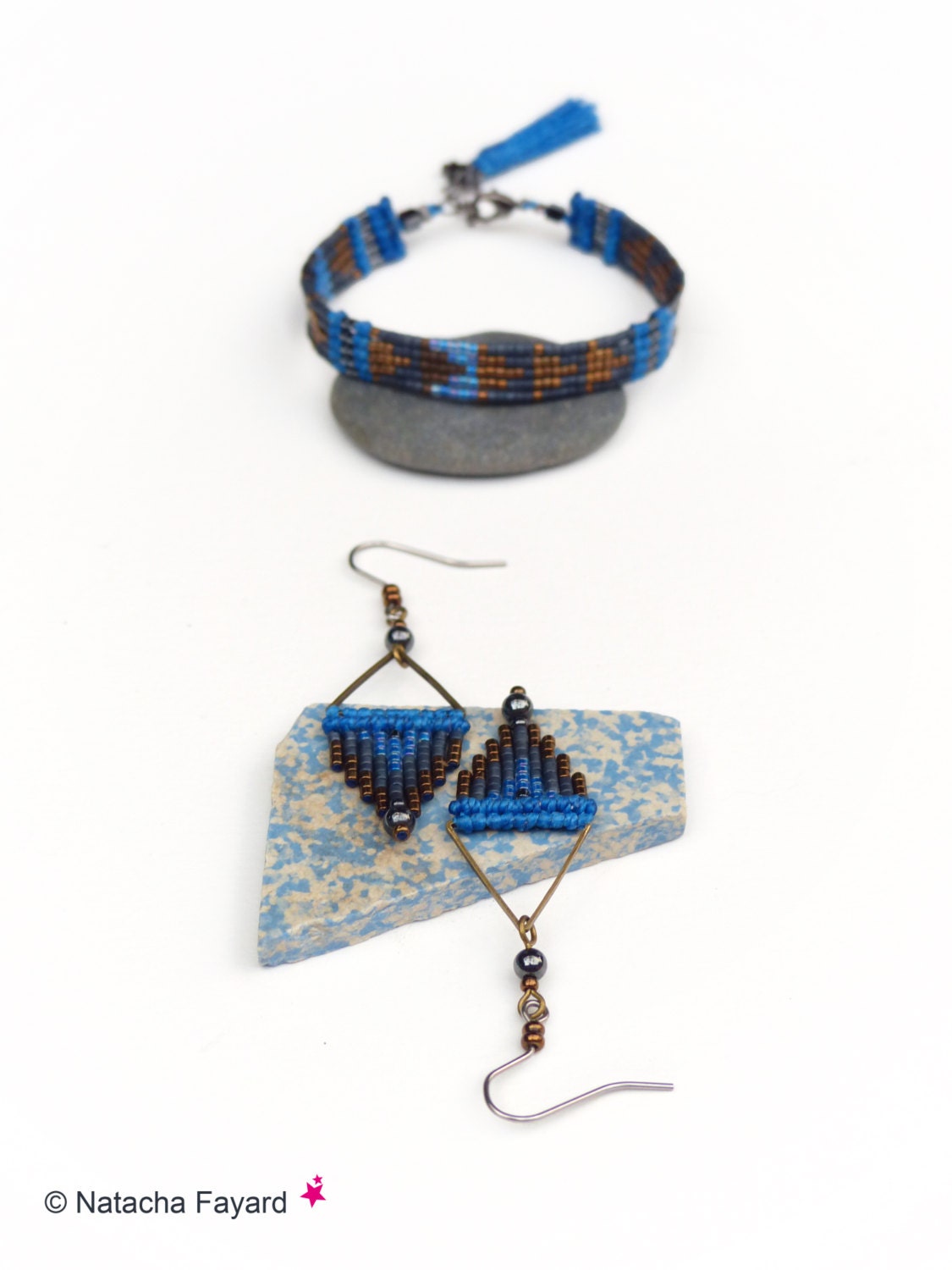 Peut inclure: Un ensemble de bijoux en perles bleues et brunes comprenant un bracelet avec un pompon et une paire de boucles d'oreilles triangulaires.