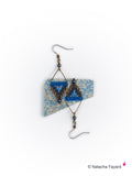 Peut inclure: Une paire de boucles d'oreilles en perles bleues et noires avec un motif géométrique. Les boucles d'oreilles sont suspendues à des crochets argentés.