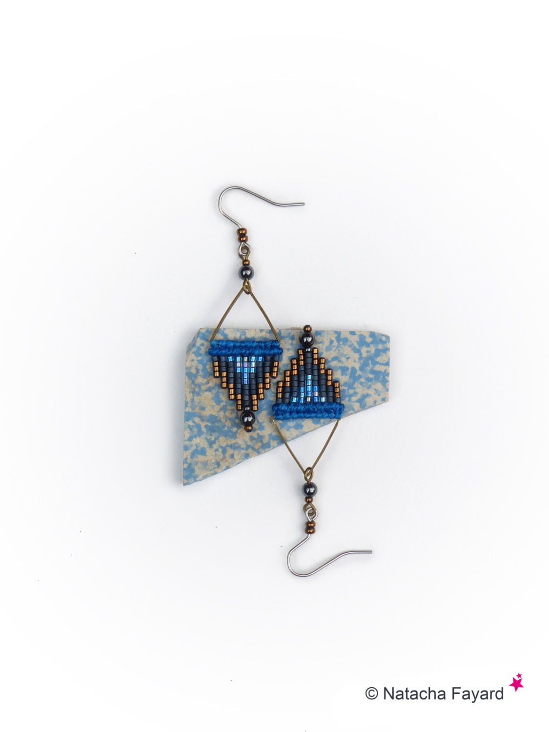 Peut inclure: Une paire de boucles d'oreilles en perles bleues et noires avec un motif géométrique. Les boucles d'oreilles sont suspendues à des crochets argentés.