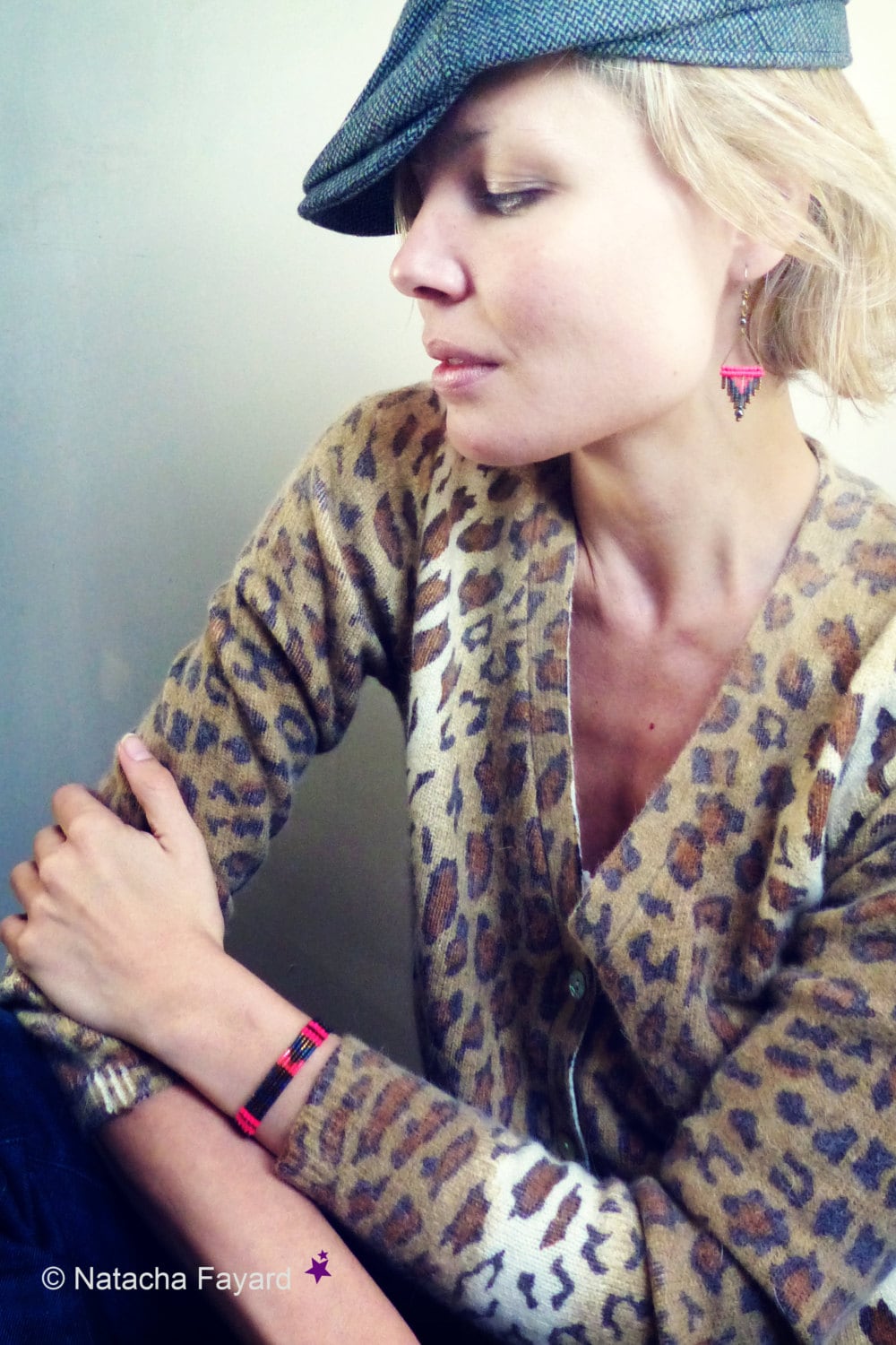 Peut inclure: Une femme portant un cardigan en tricot léopard brun et noir avec un bracelet en perles noir et rouge au poignet. Elle porte également une boucle d'oreille en perles noir et rouge.