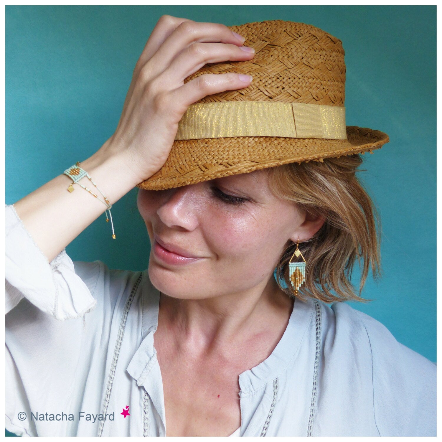 Peut inclure: Une femme portant un chapeau de paille avec un bandeau doré, une chemise blanche et des boucles d'oreilles et des bracelets en perles. Les boucles d'oreilles et les bracelets sont faits de perles turquoise et dorées.