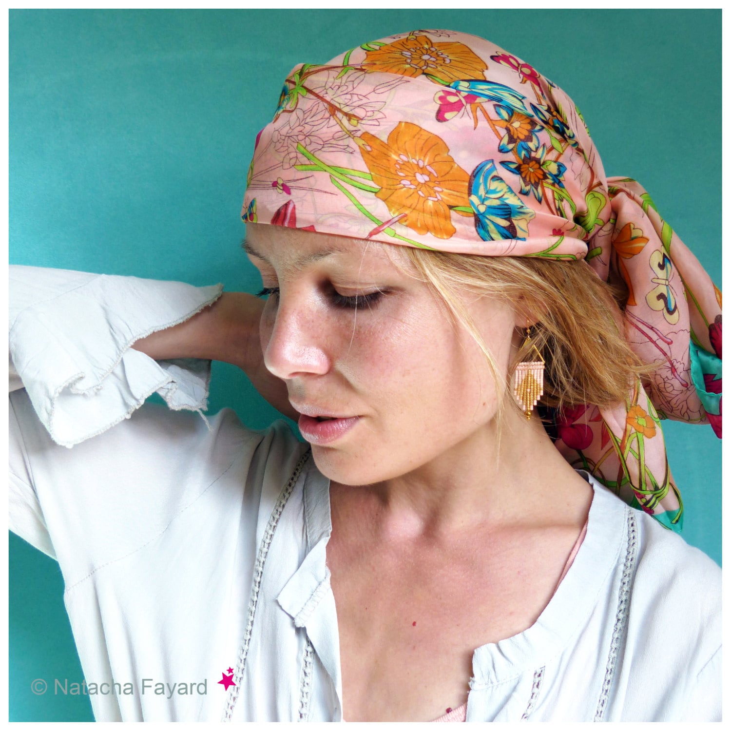 Peut inclure: Une femme aux cheveux blonds porte une chemise blanche et un foulard floral rose. Elle porte des boucles d'oreilles en perles dorées et roses.
