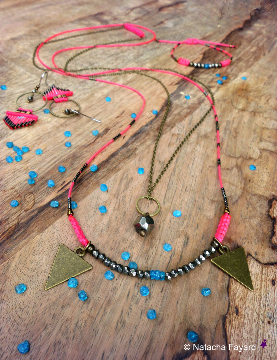 Peut inclure: Un collier de perles rose et noir avec un pendentif triangulaire et un petit charme en métal. Le collier est fait de petites perles rondes et a un design simple. Le pendentif est une grande forme triangulaire avec une finition rustique. Le charme est une petite forme ronde avec une finition lisse.